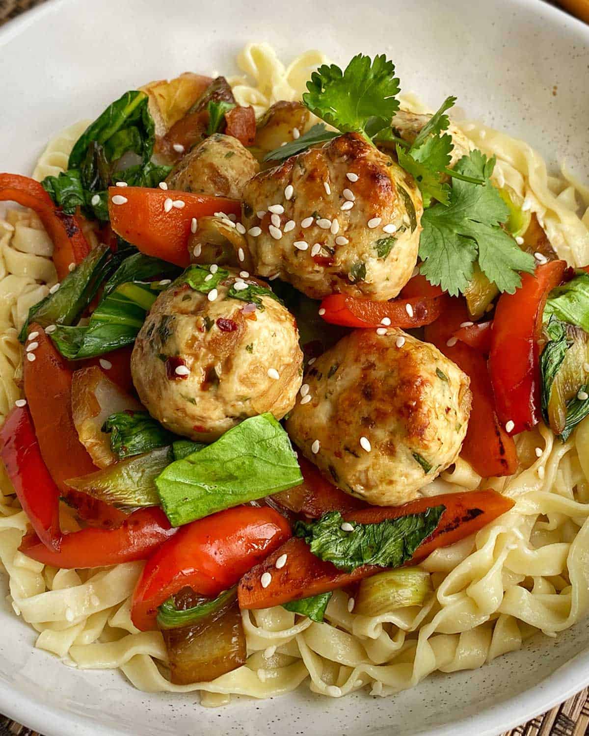 A close up of Chicken Meatballs with Noodles in a white bowl.