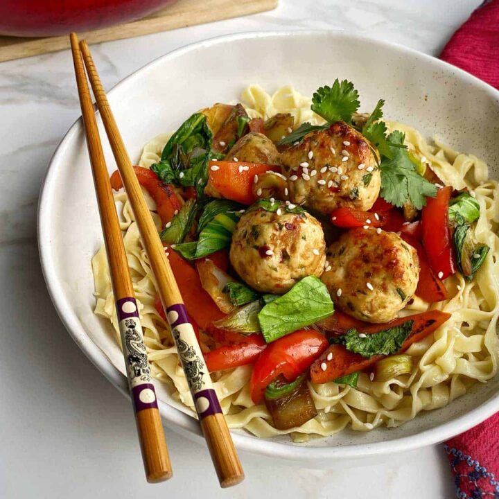 Chicken Meatballs with Noodles served in a white bowl with chopsticks on the side.