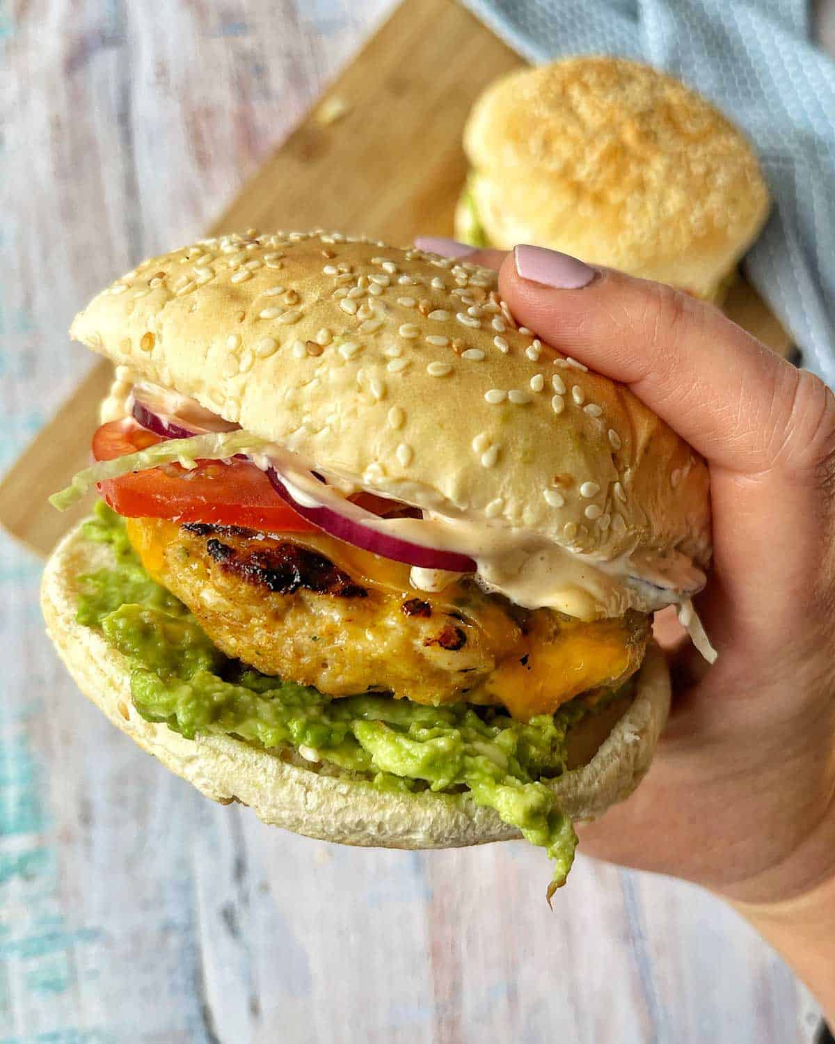 A hand holding a Mexican Chicken Burger.