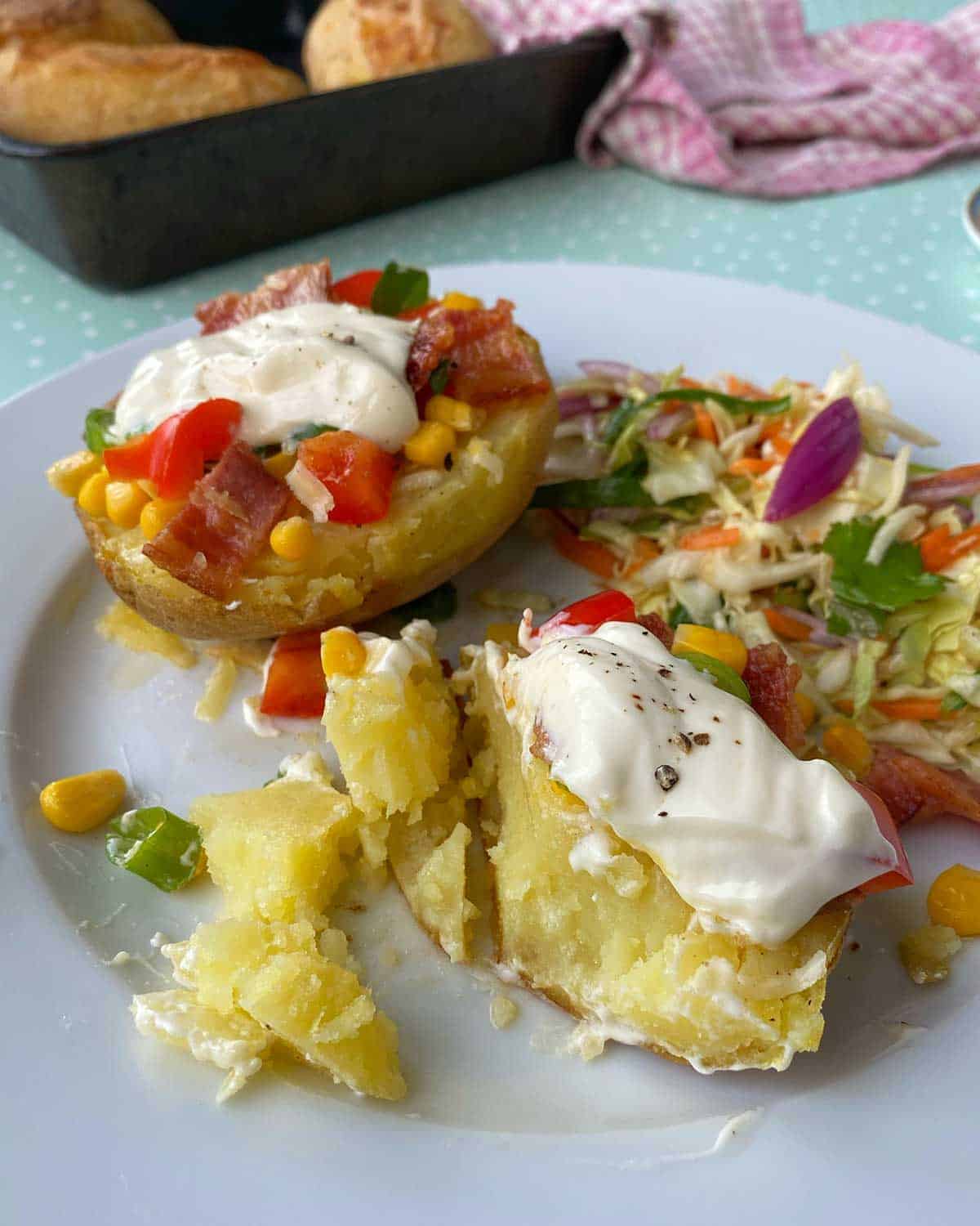 Loaded Baked Potatoes on a white plate served with salad.