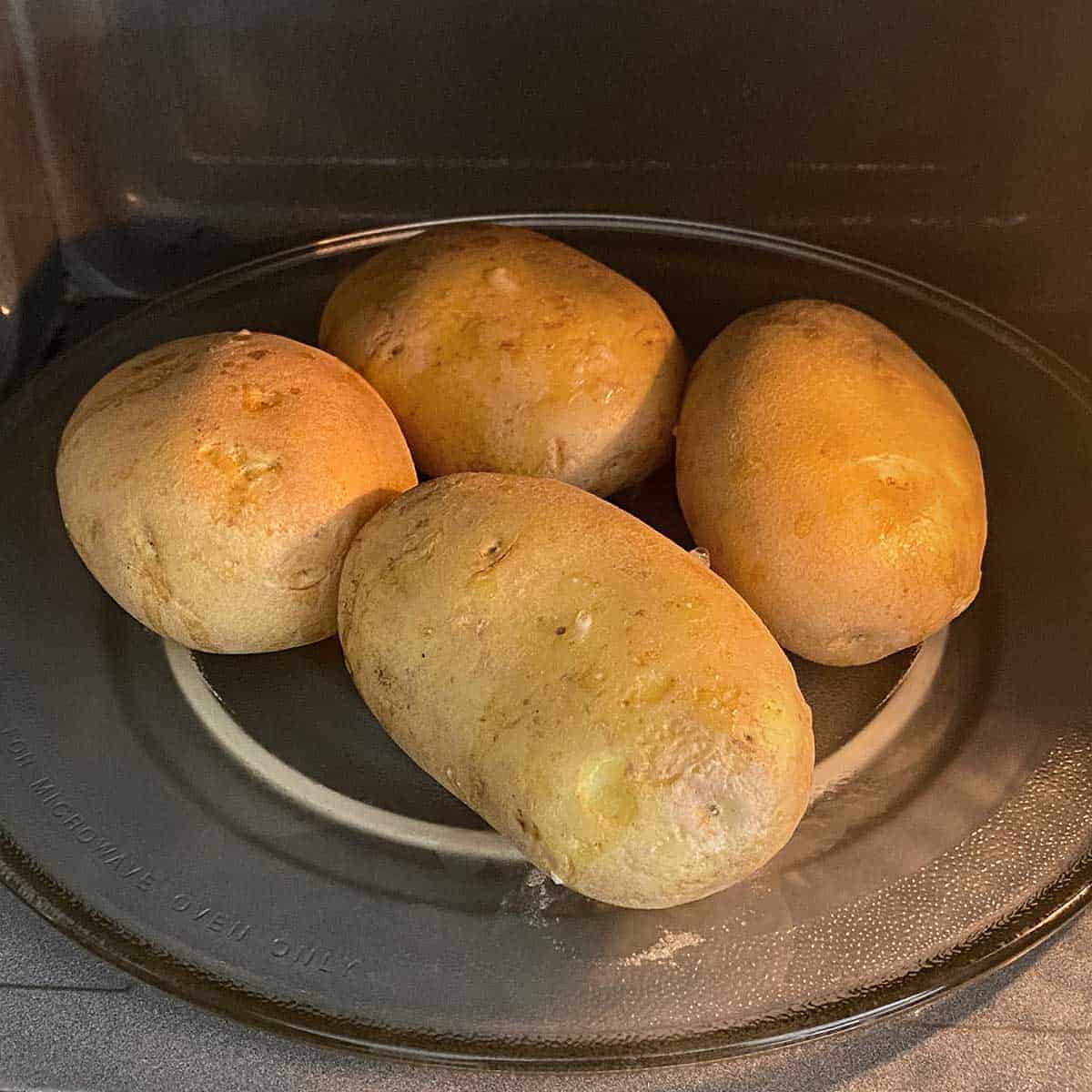 4 potatoes inside a microwave.