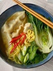 Dumpling Noodle Soup in a blue bowl with chopsticks resting on the side.