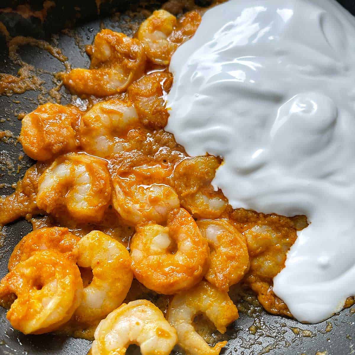 Prawns and coconut cream in a frying pan.