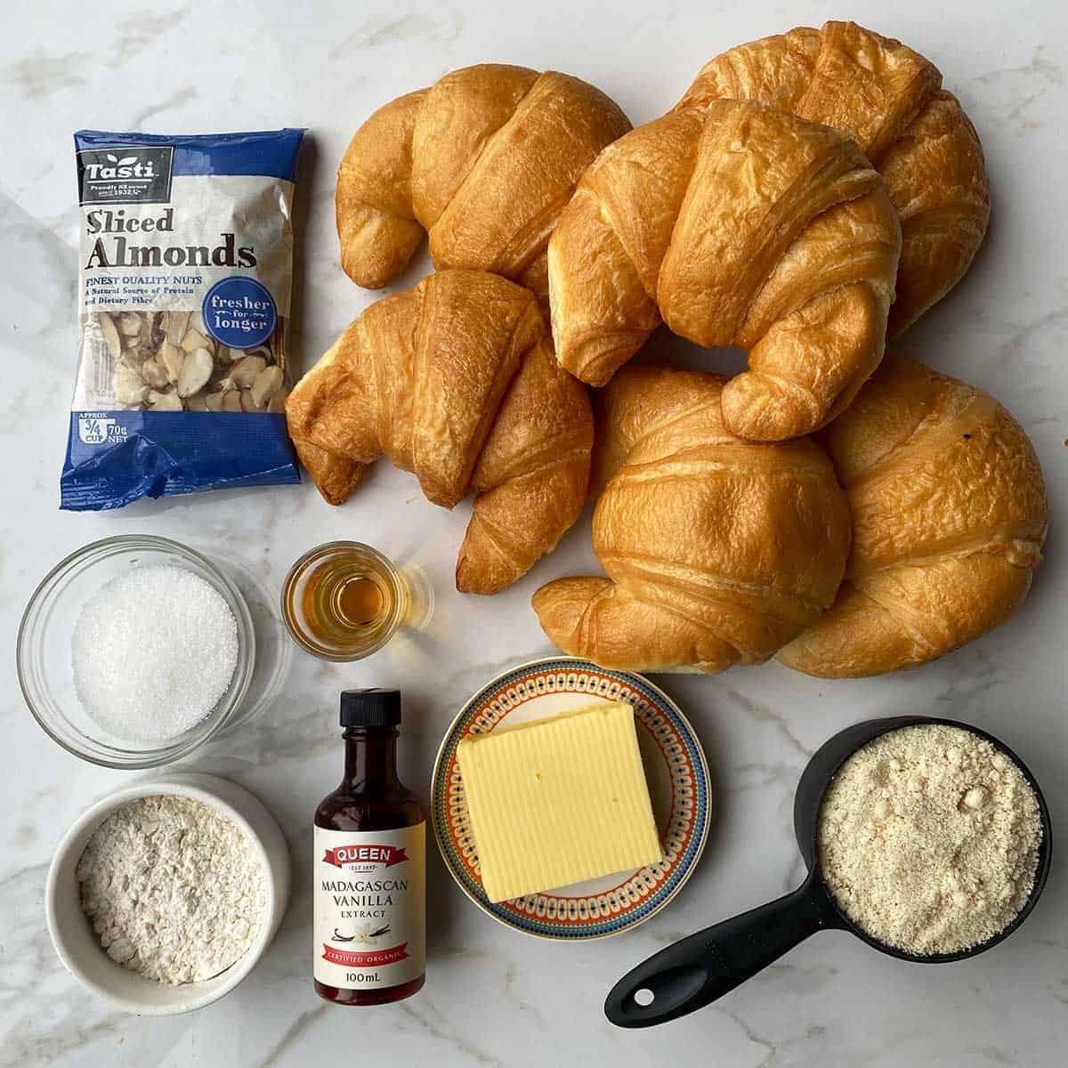 The ingredients for Almond Croissants on a white bench.