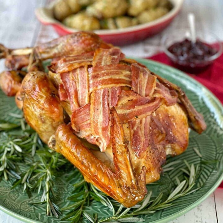 A Bacon Covered Roast Turkey sitting on a green plate.