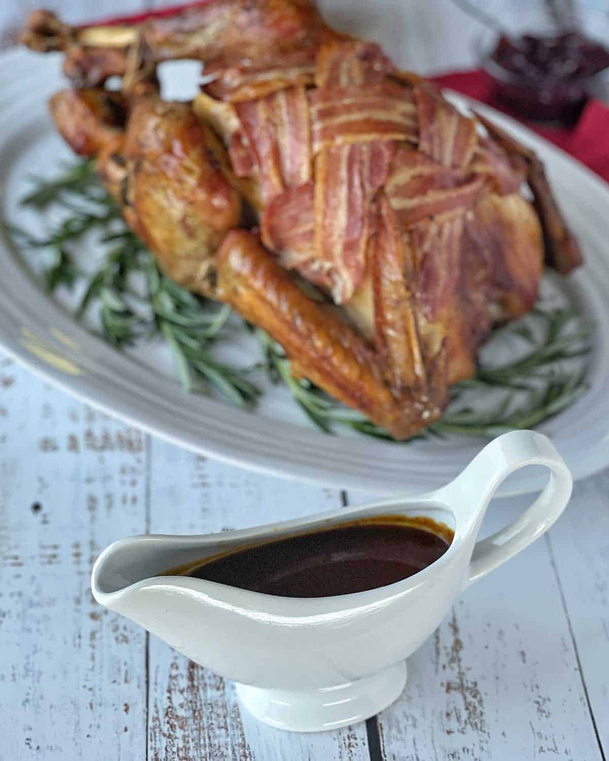 A Roast Turkey in the background and a jug of gravy in the foreground.