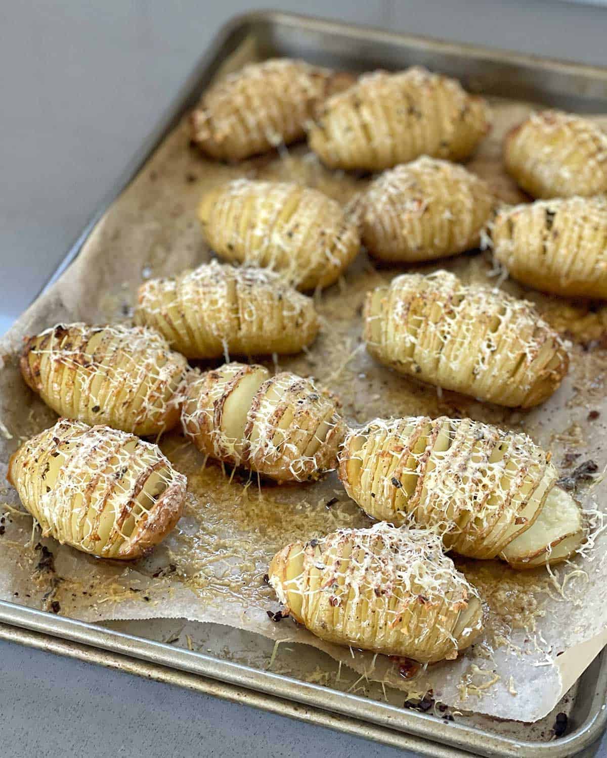 Cooked Hasselback Potatoes sitting on a lined baking tray.