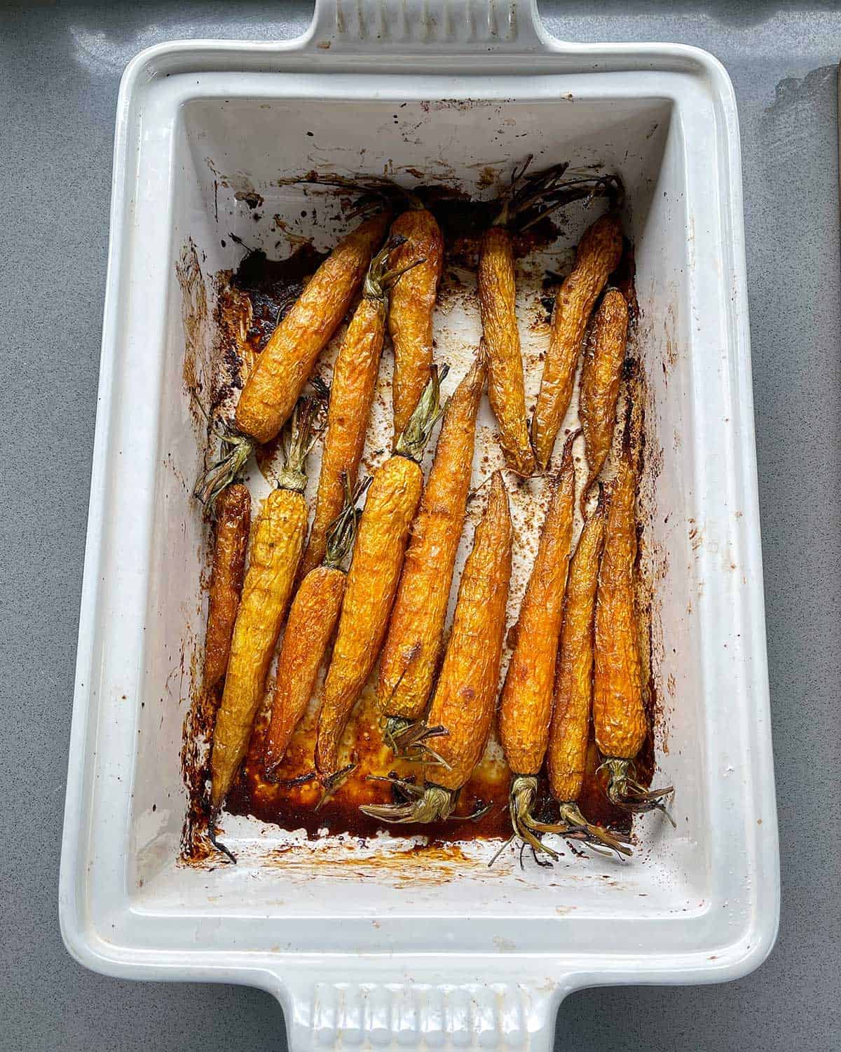 Cooked carrots in a white baking dish.