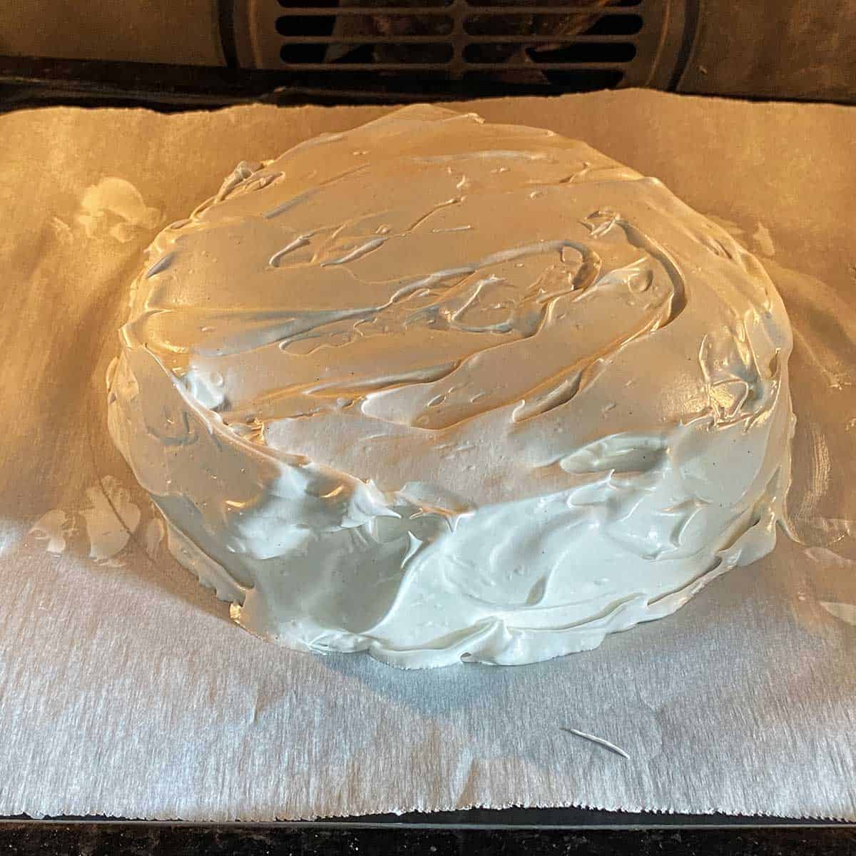 An uncooked pavlova going into the oven on a baking tray.