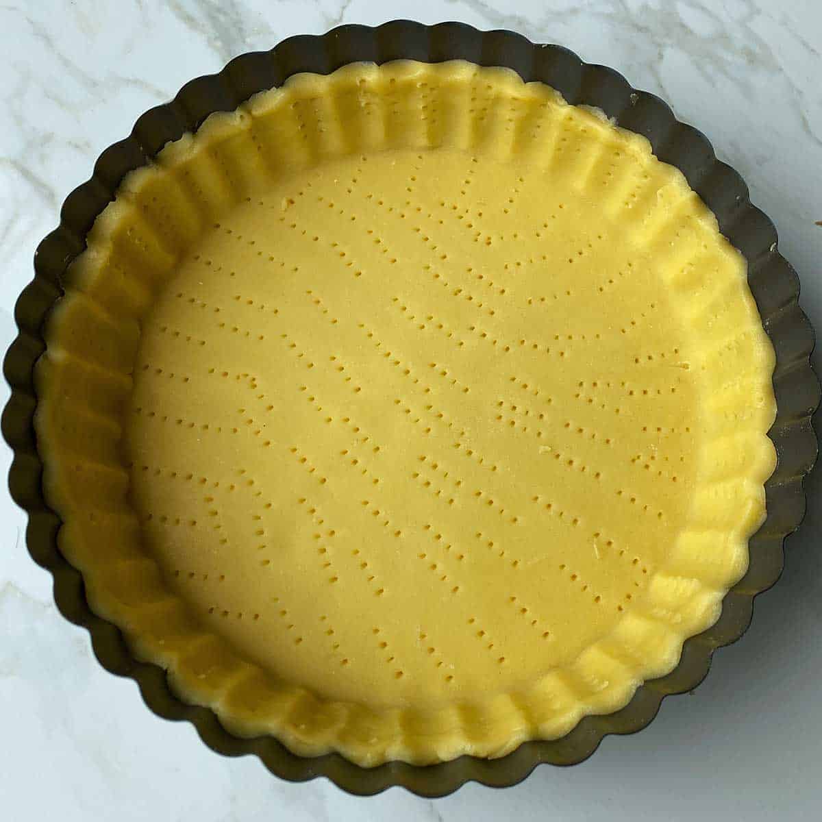 A tart tin covered with shortcrust pastry.