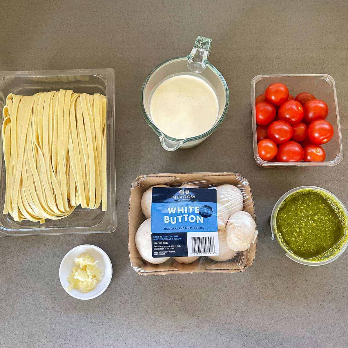 The ingredients for mushroom pesto pasta on a grey bench.
