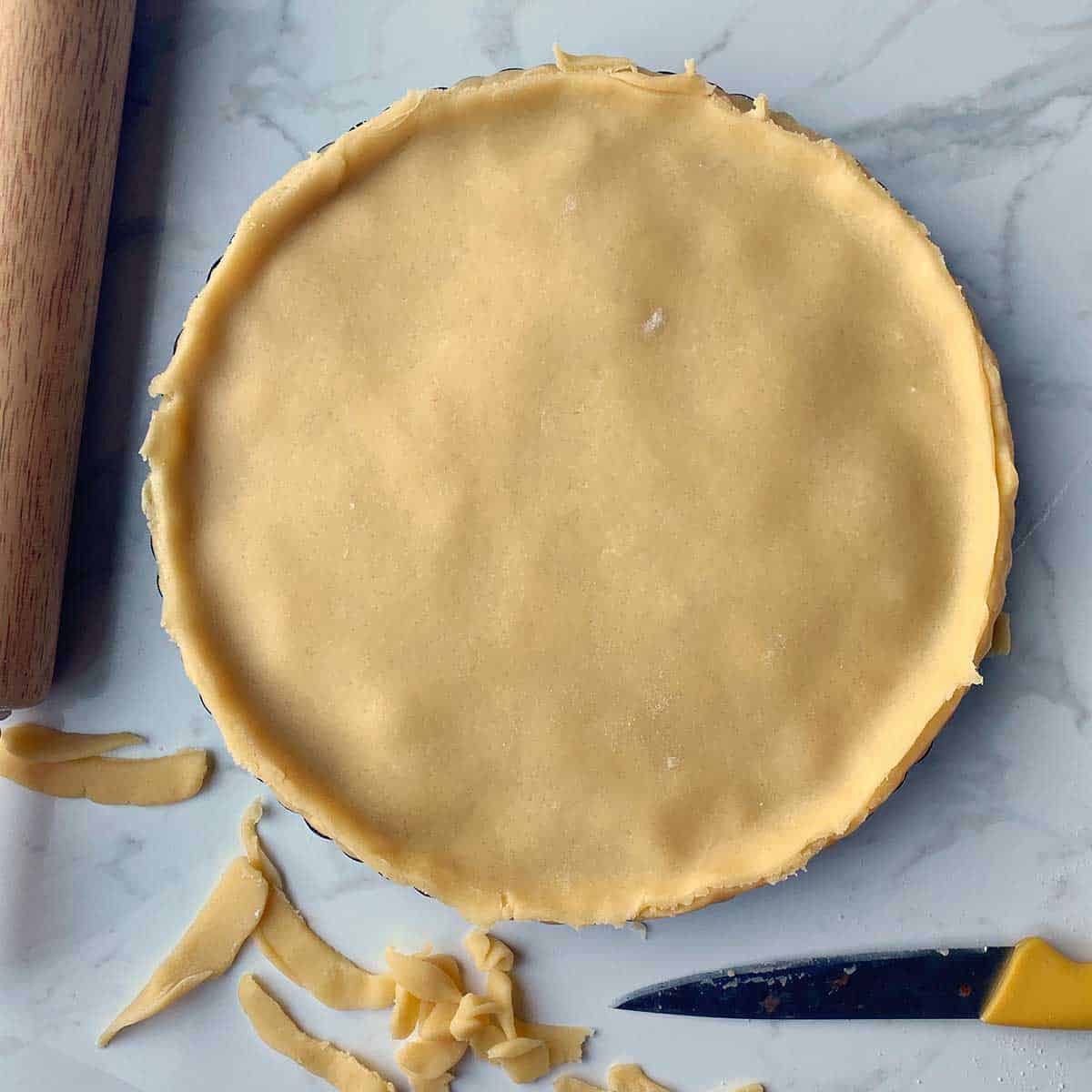 A pie with a shortcrust topping having just been trimmed of excess pastry.