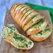 Slices of garlic bread on a wooden chopping board.