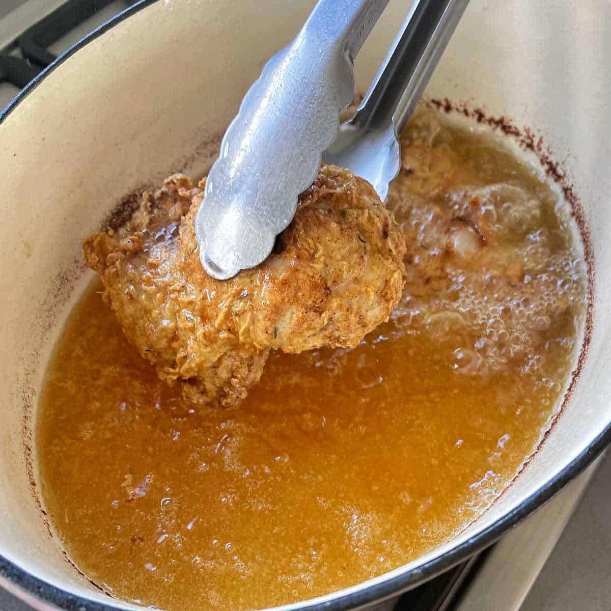 One piece of fried chicken being removed from the oil