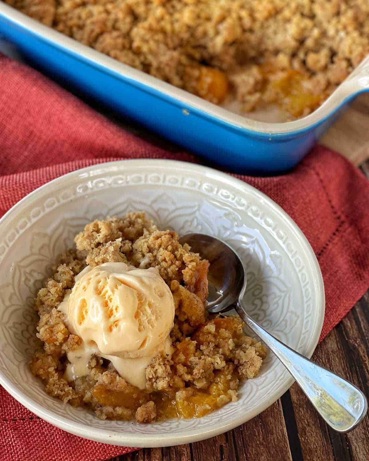Apricot crumble served with vanilla ice cream in a white bowl