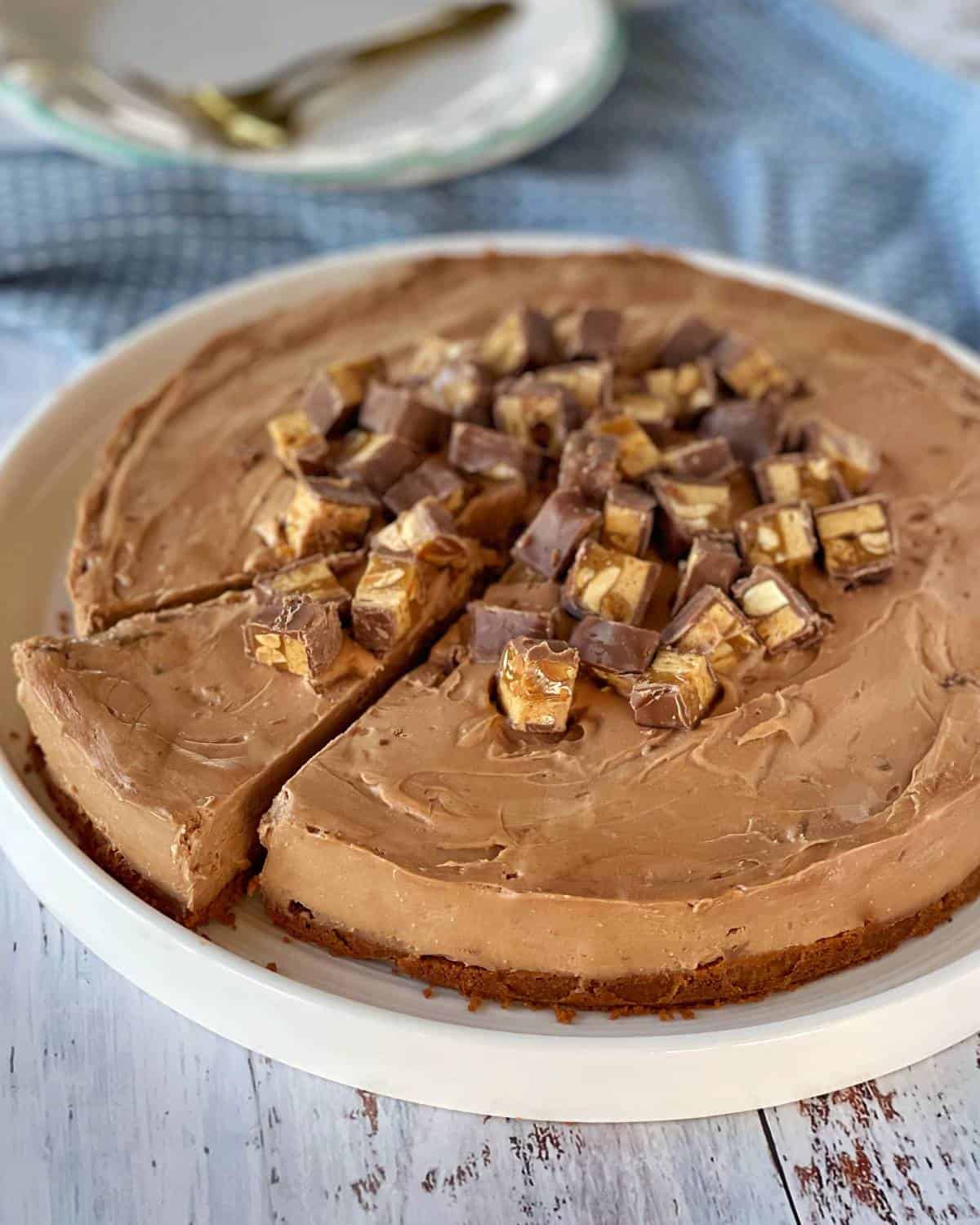 Snickers cheesecake served on a large white plate
