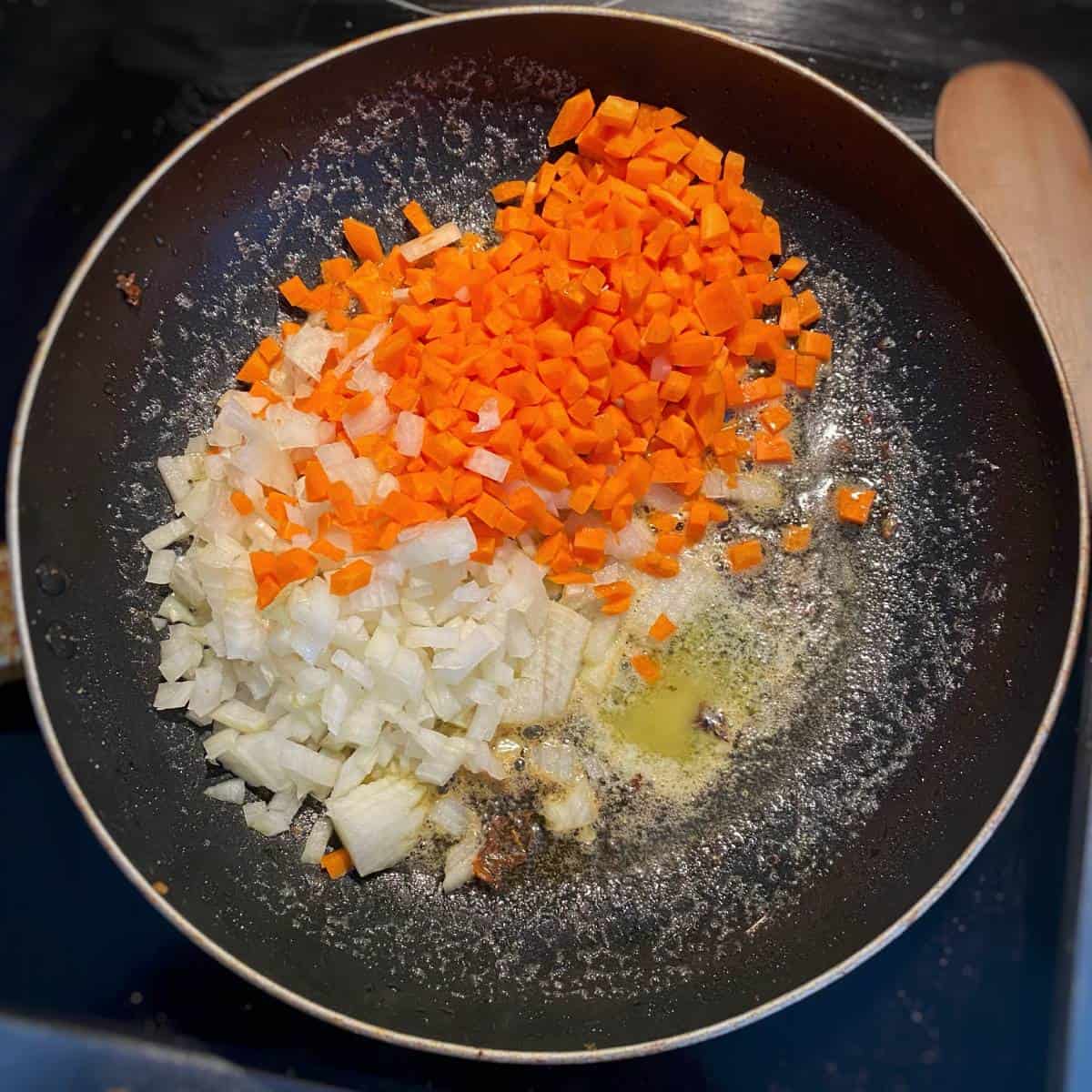 The chopped ingredients for cheesy chicken pasta frying in a fry pan