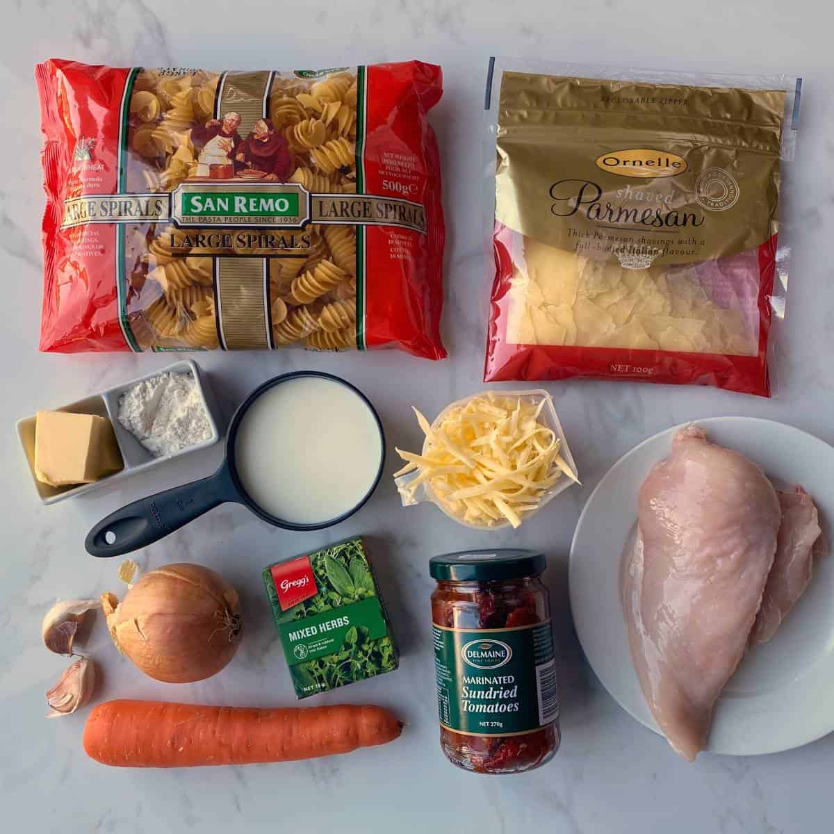 Ingredients for cheesy chicken pasta sitting on a grey bench