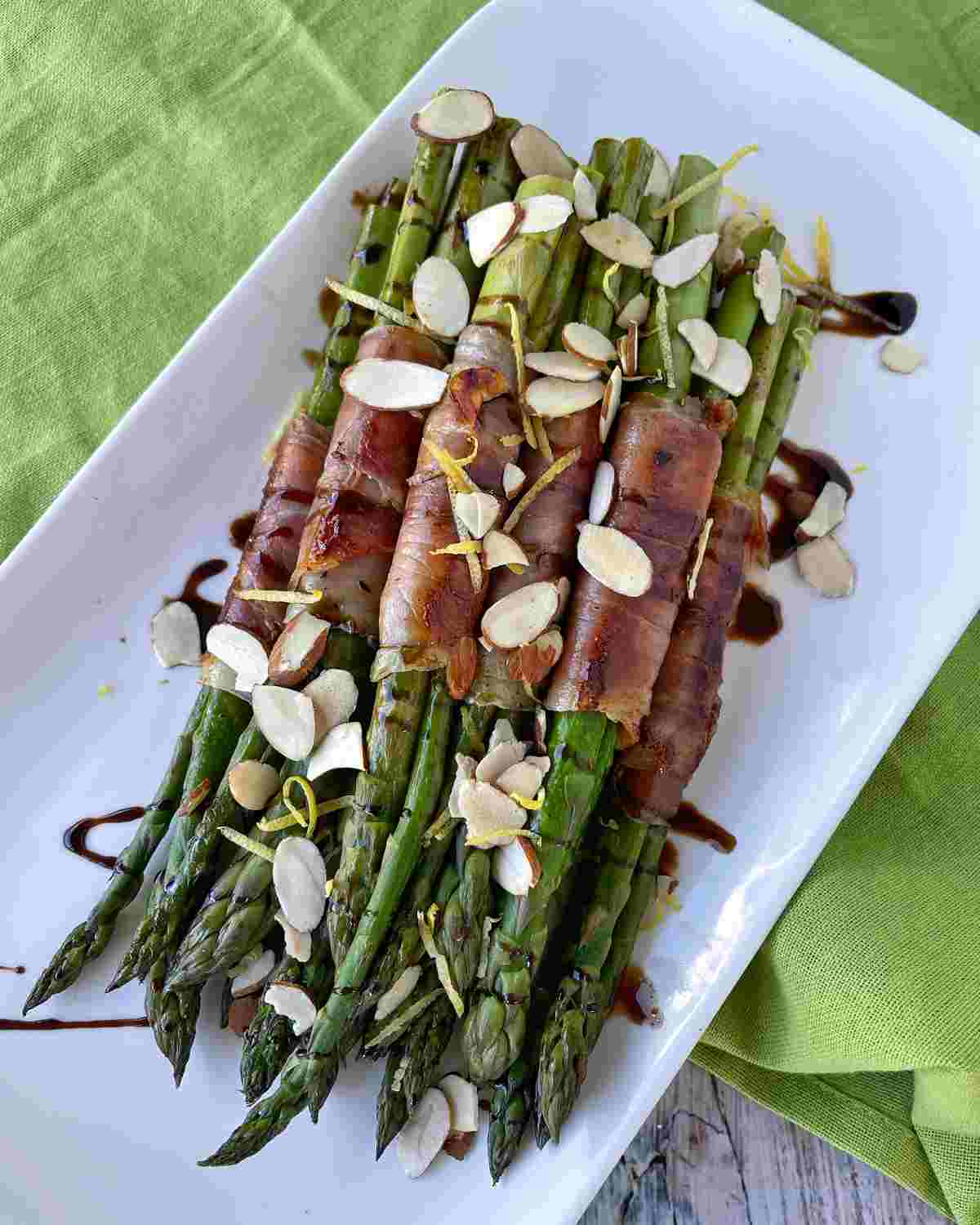 Asparagus wrapped in prosciutto served on a white dish