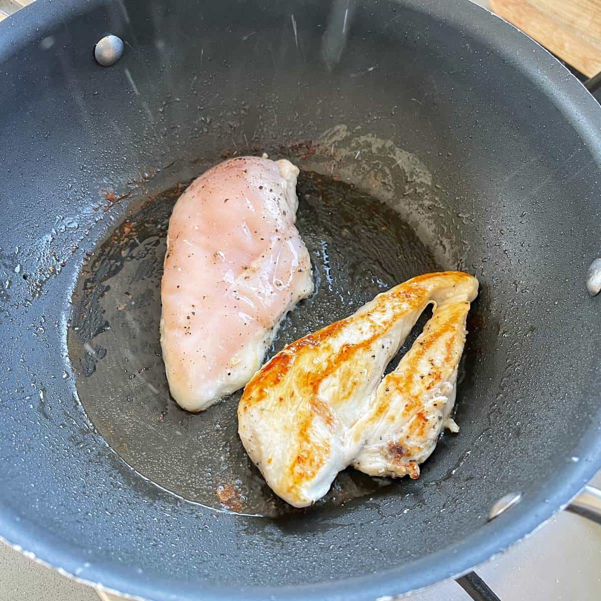 Chicken breast frying in a frypan