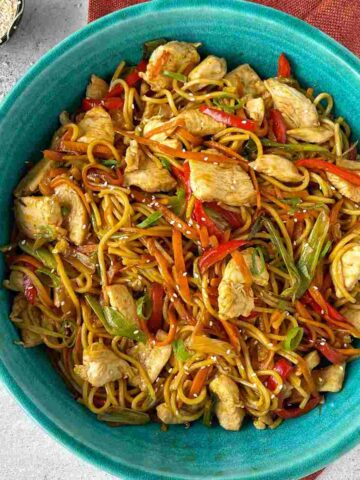 Chicken Chow Mein served in a large blue bowl sitting on a grey marble bench