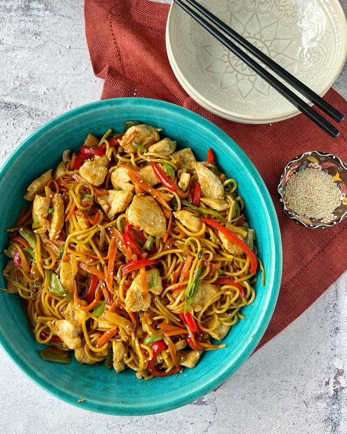 Chicken Chow Mein served in a large blue bowl sitting on a grey marble bench