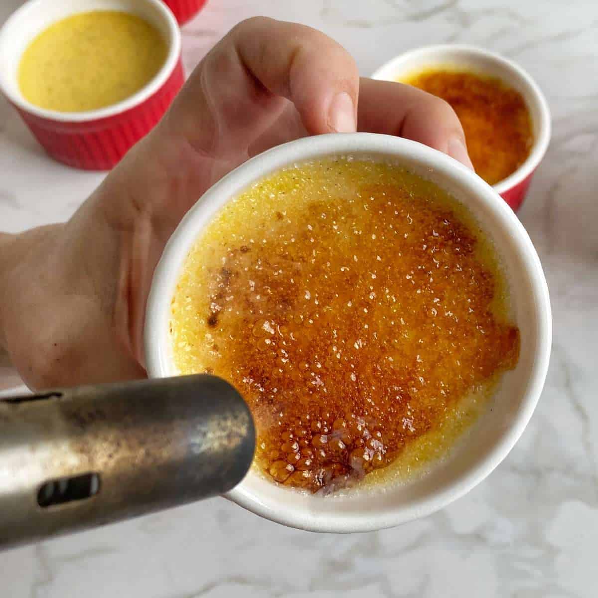 Creme Brulee mixture being touched so that the sugar hardens on the top