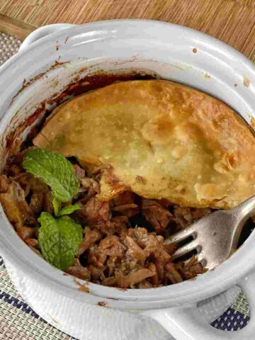 Cooked lamb and mint pie showing the pie mixture with a fork
