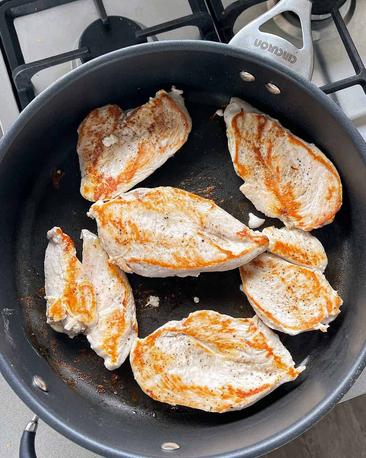 Grilled chicken breast cooking in a non stick frying pan.