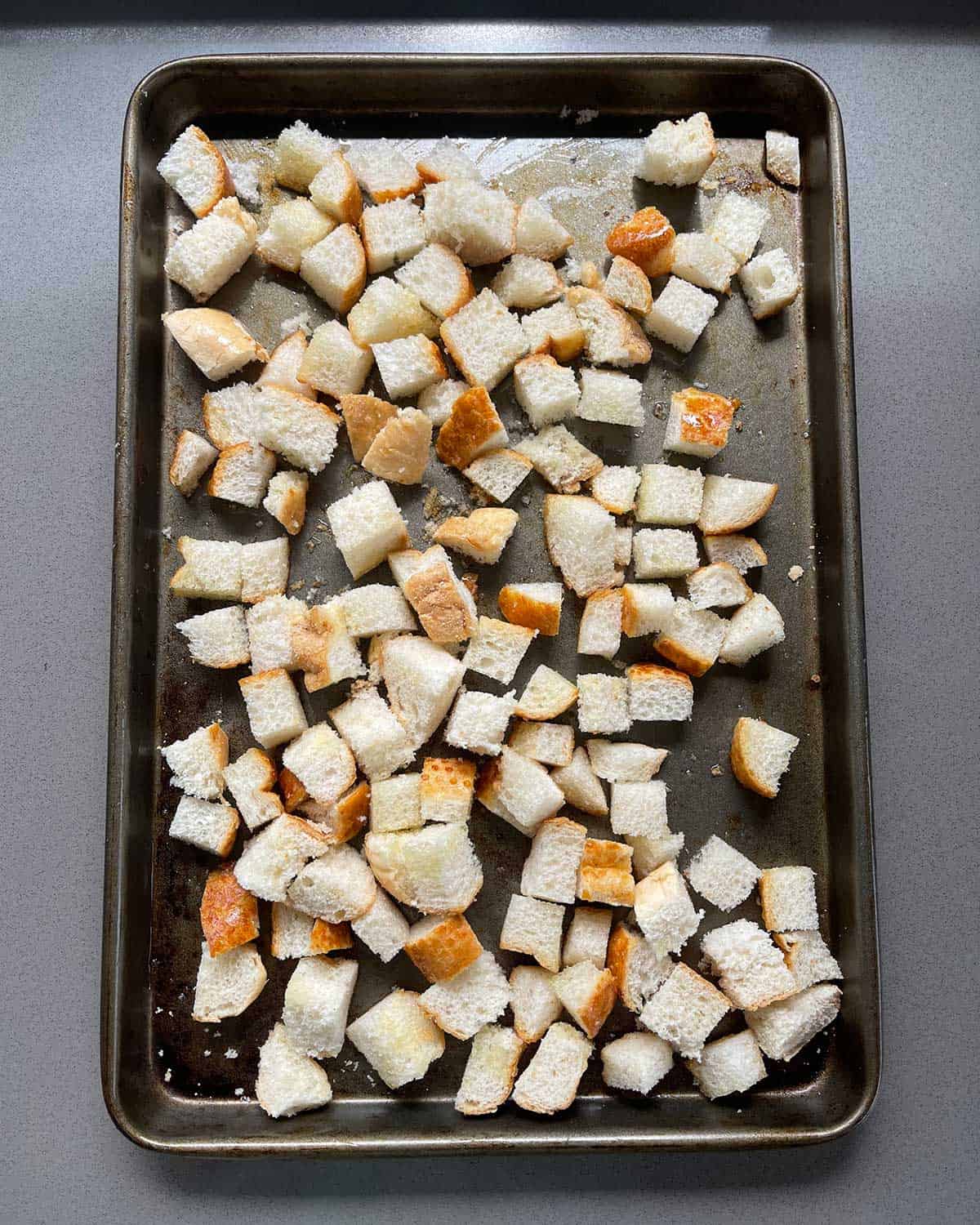 Small pieces of bread cut up on an oven tray.