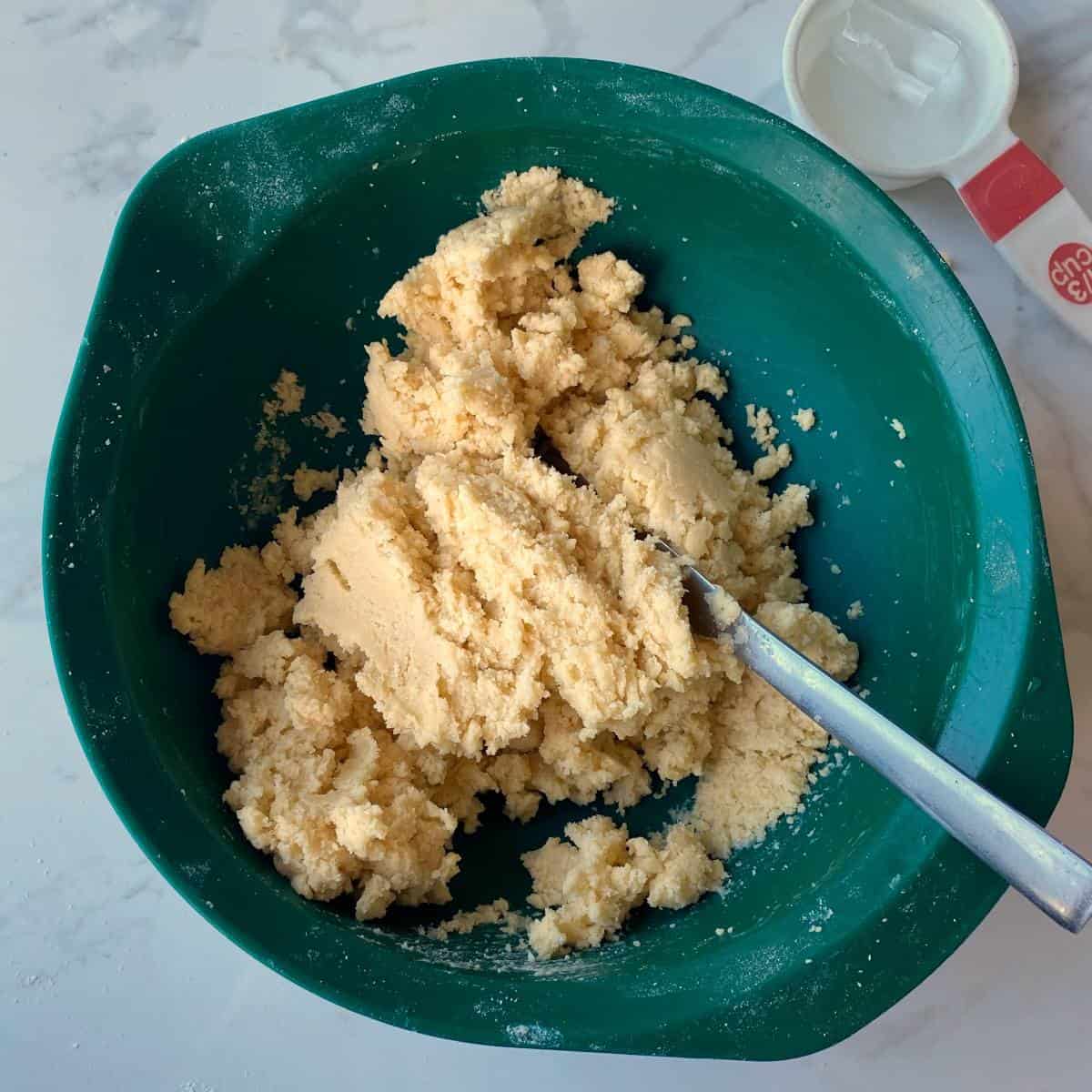 The mixture for short crust pastry in a green mixing bowl