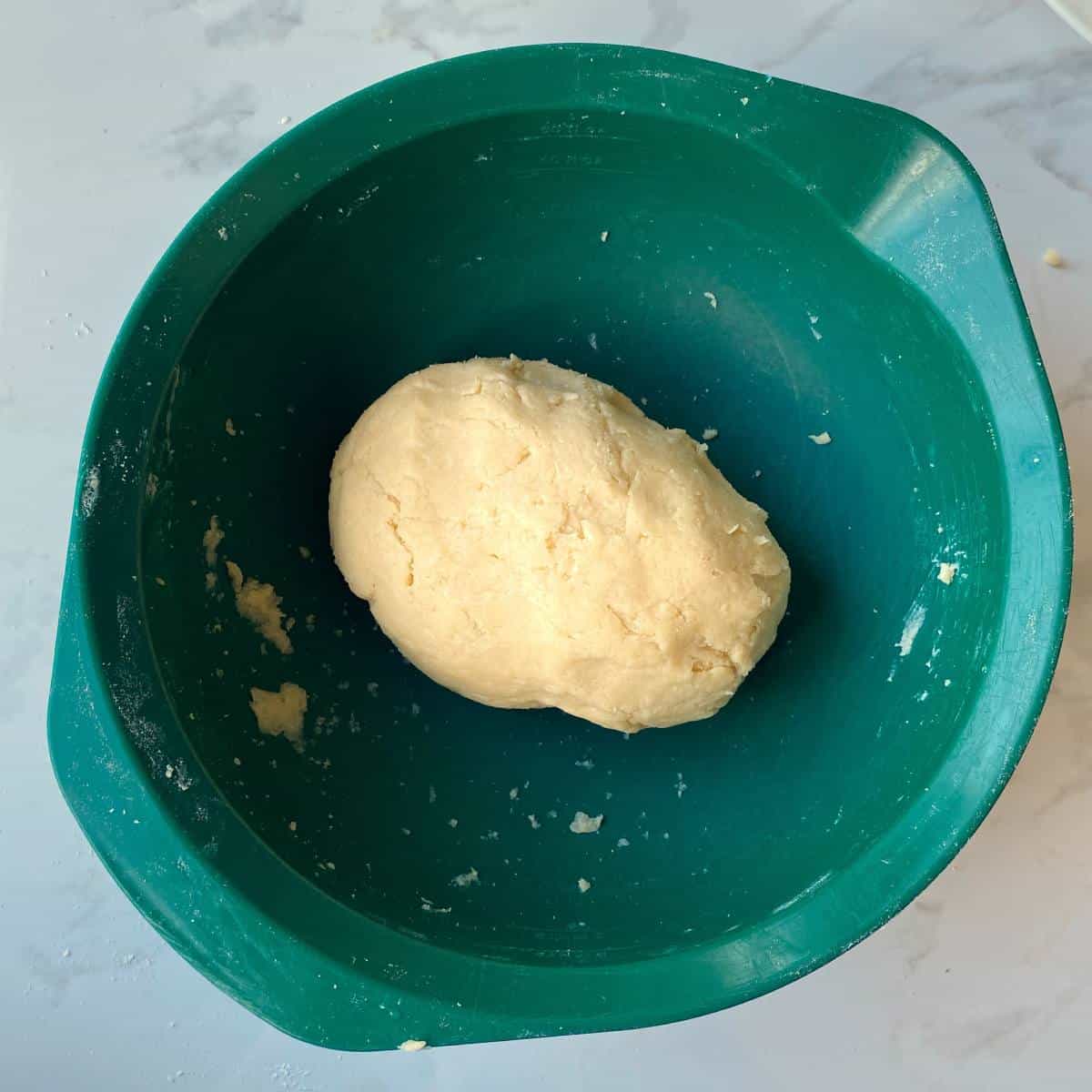 The mixture for short crust pastry in a green mixing bowl - mixed into a ball