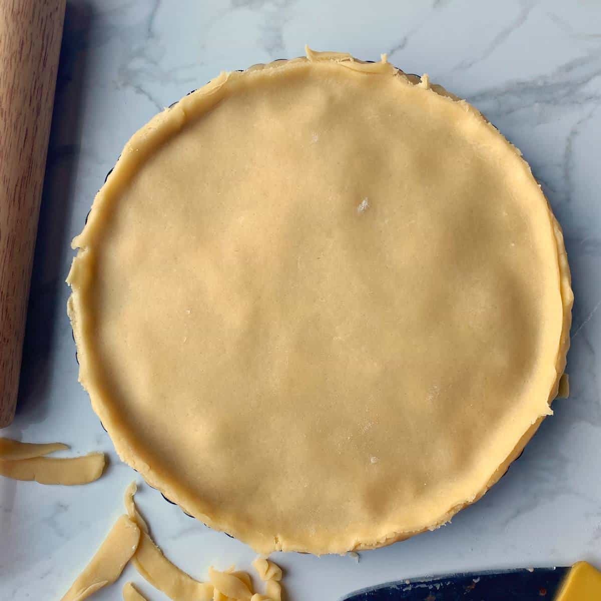 Uncooked apricot short crust pie sitting on a marble bench top