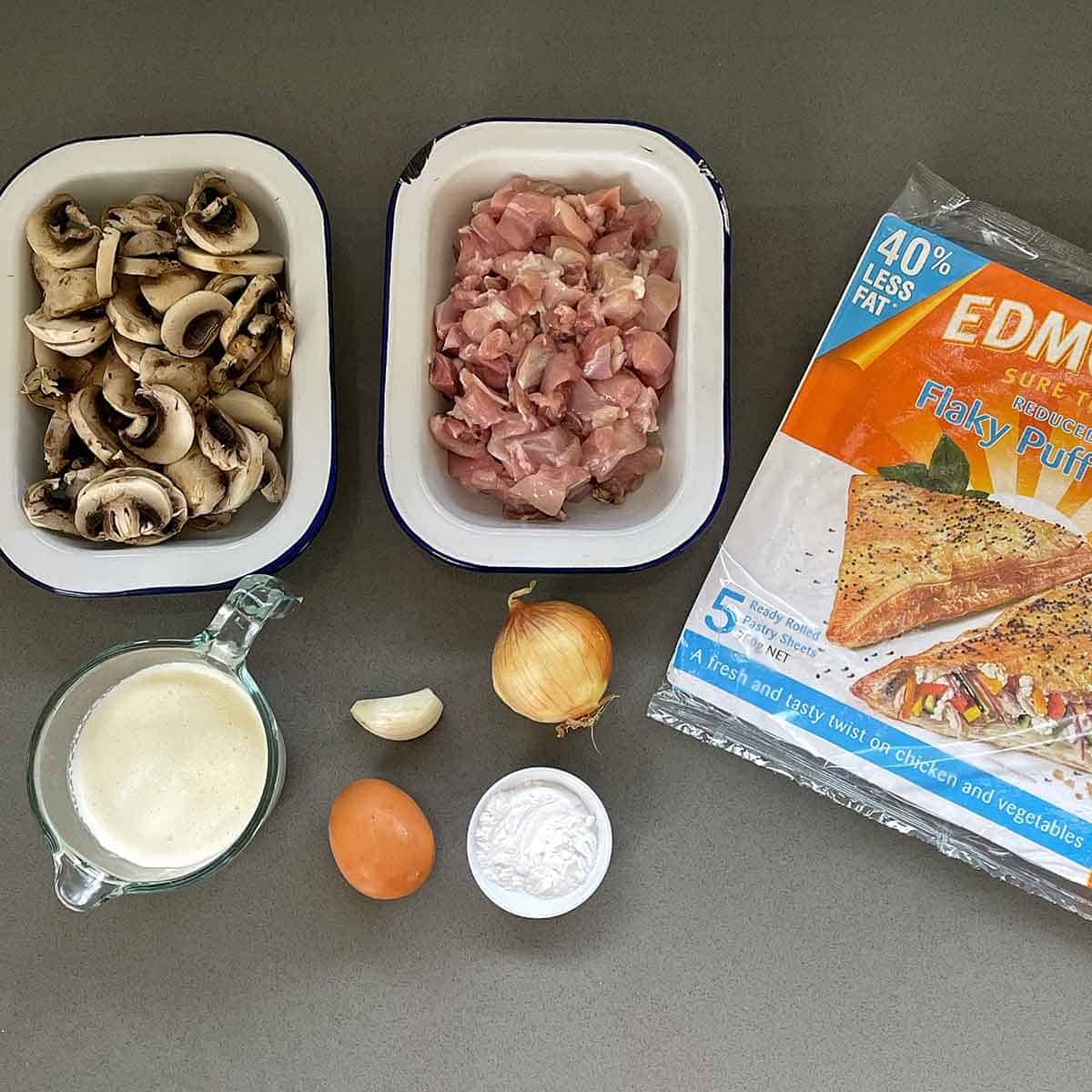 The ingredients for chicken and mushroom pie on a grey bench