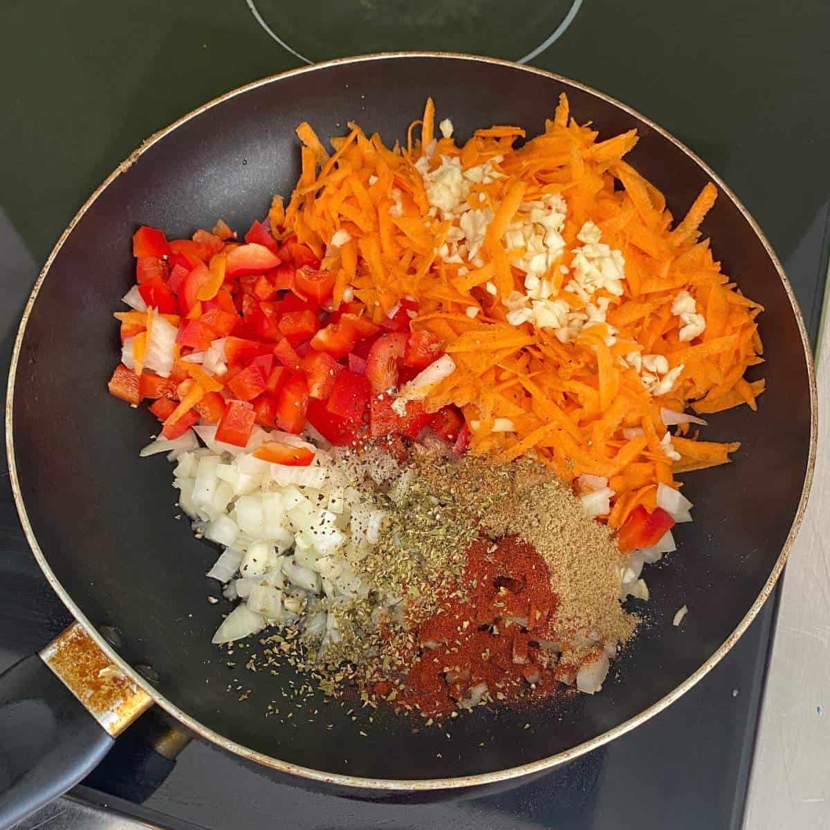 The vegetables, herbs and spices being fried in a fry pan over a medium heat