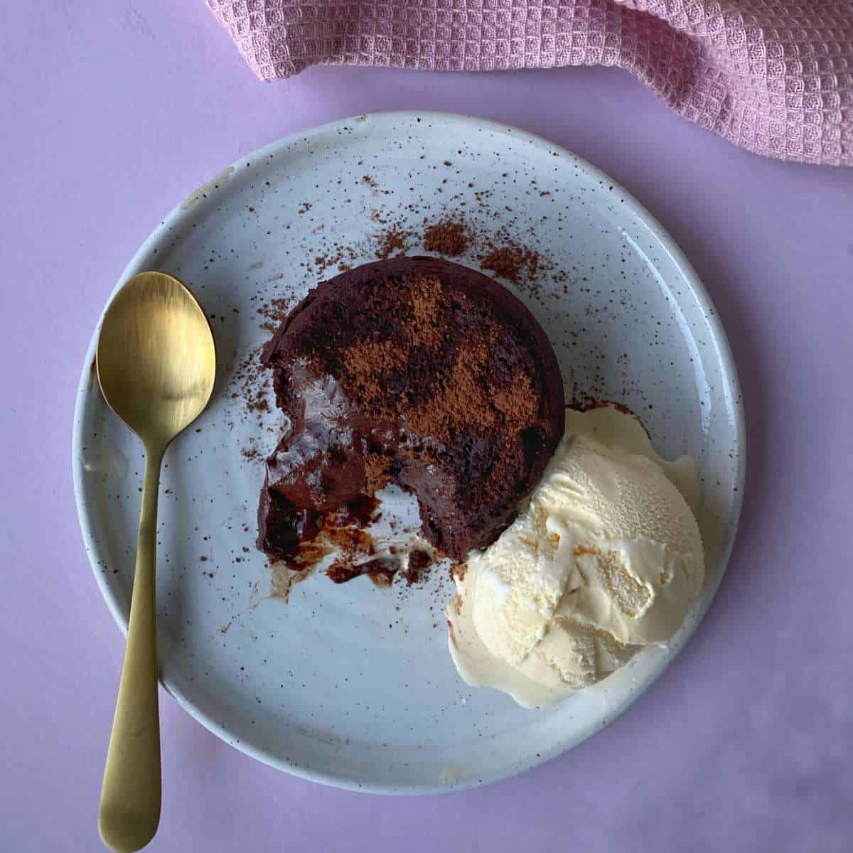 A Chocolate Fondant with a gooey chocolate centre on a plate with a scoop of ice cream.