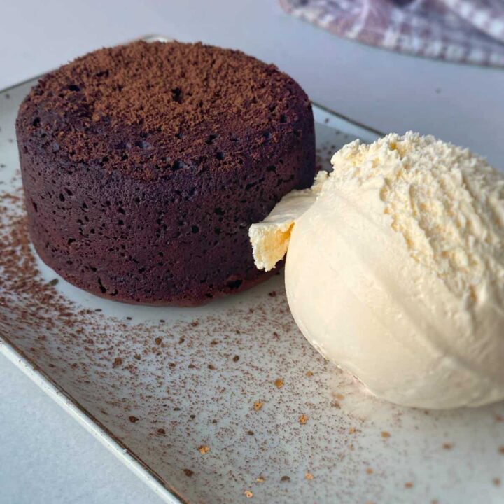A chocolate fondant and a scoop of vanilla ice cream on a plate.