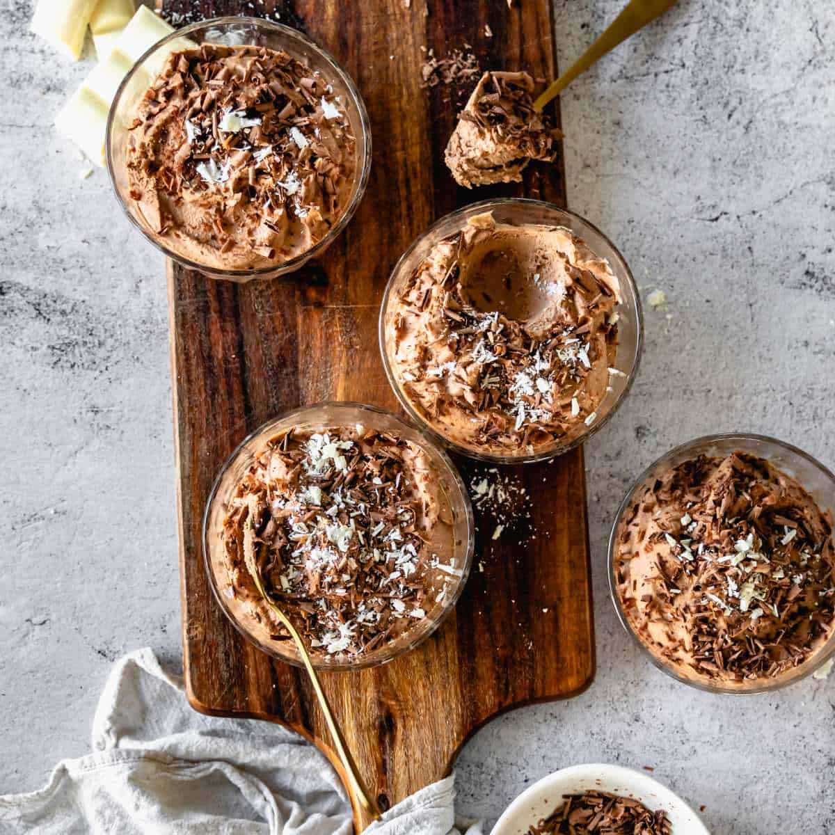 Four individual chocolate mousse's served in small glass dishes with shredded chocolate and coconut sprinkled on top