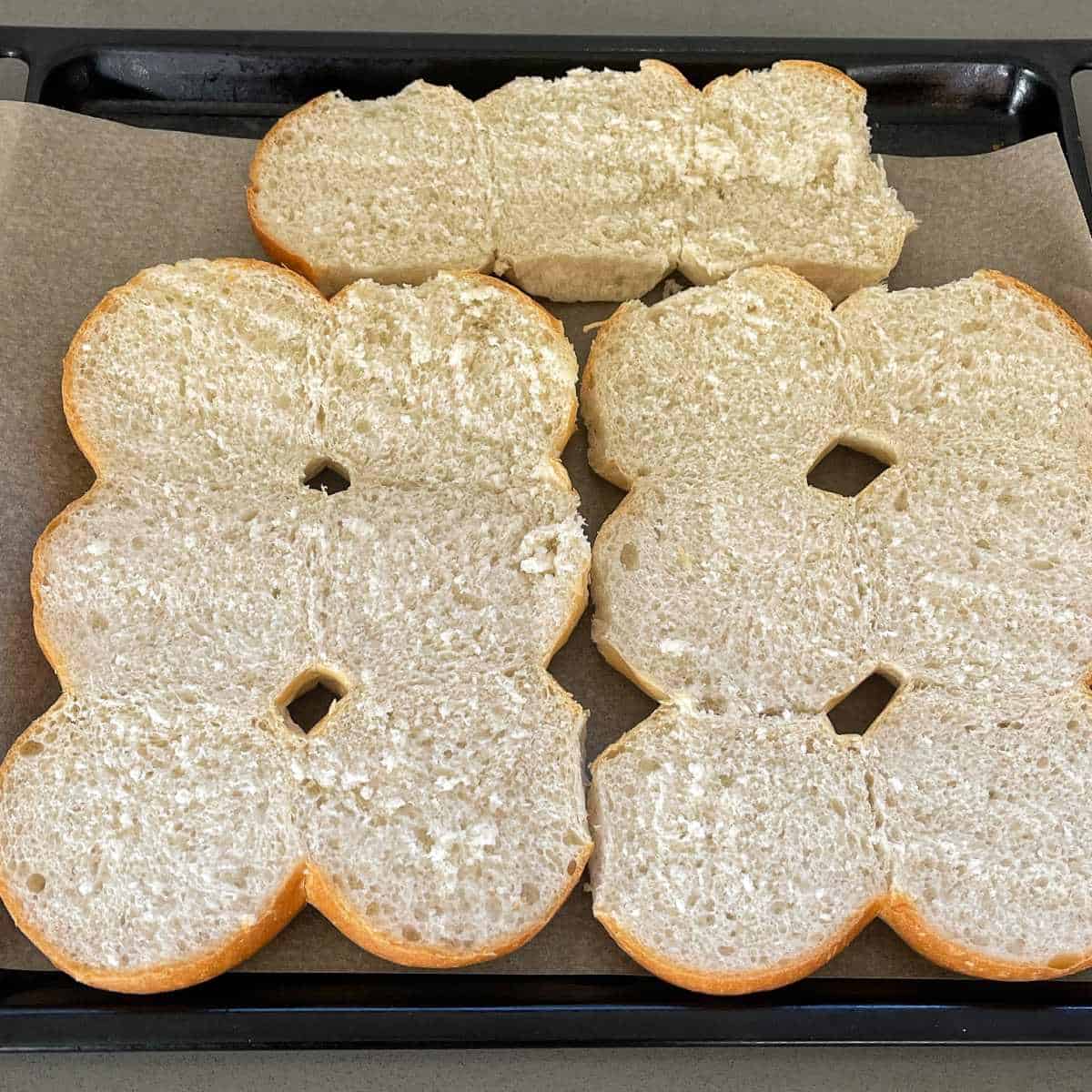 Slider buns cut in half on a lined oven tray
