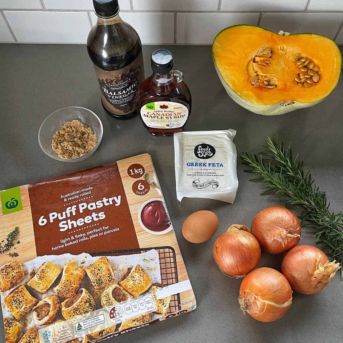 The ingredients for pumpkin and feta tart sitting on a grey bench top