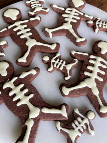 Large and small skeleton cookies on a white platter.