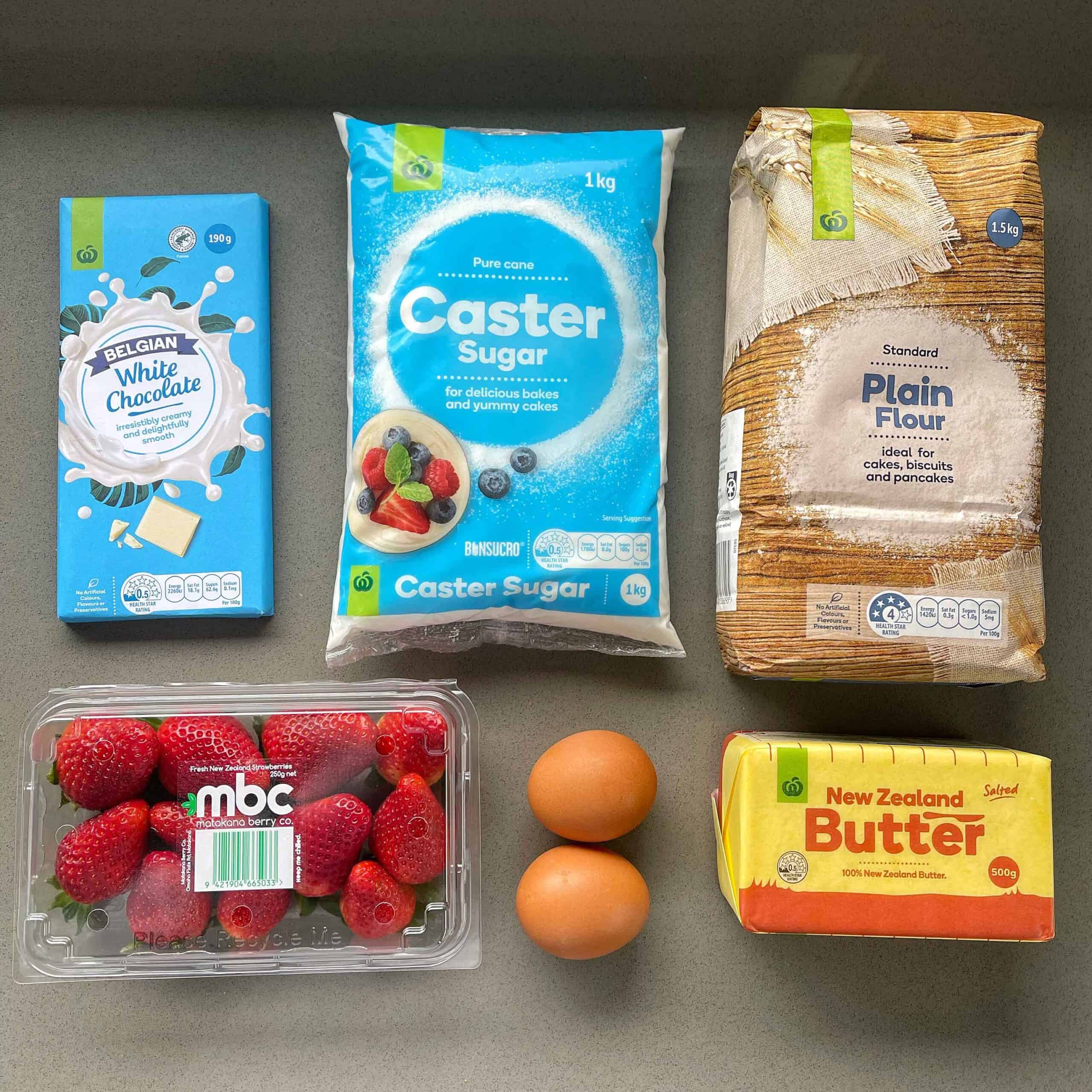 The ingredients for white chocolate and strawberry blondies on a grey bench.