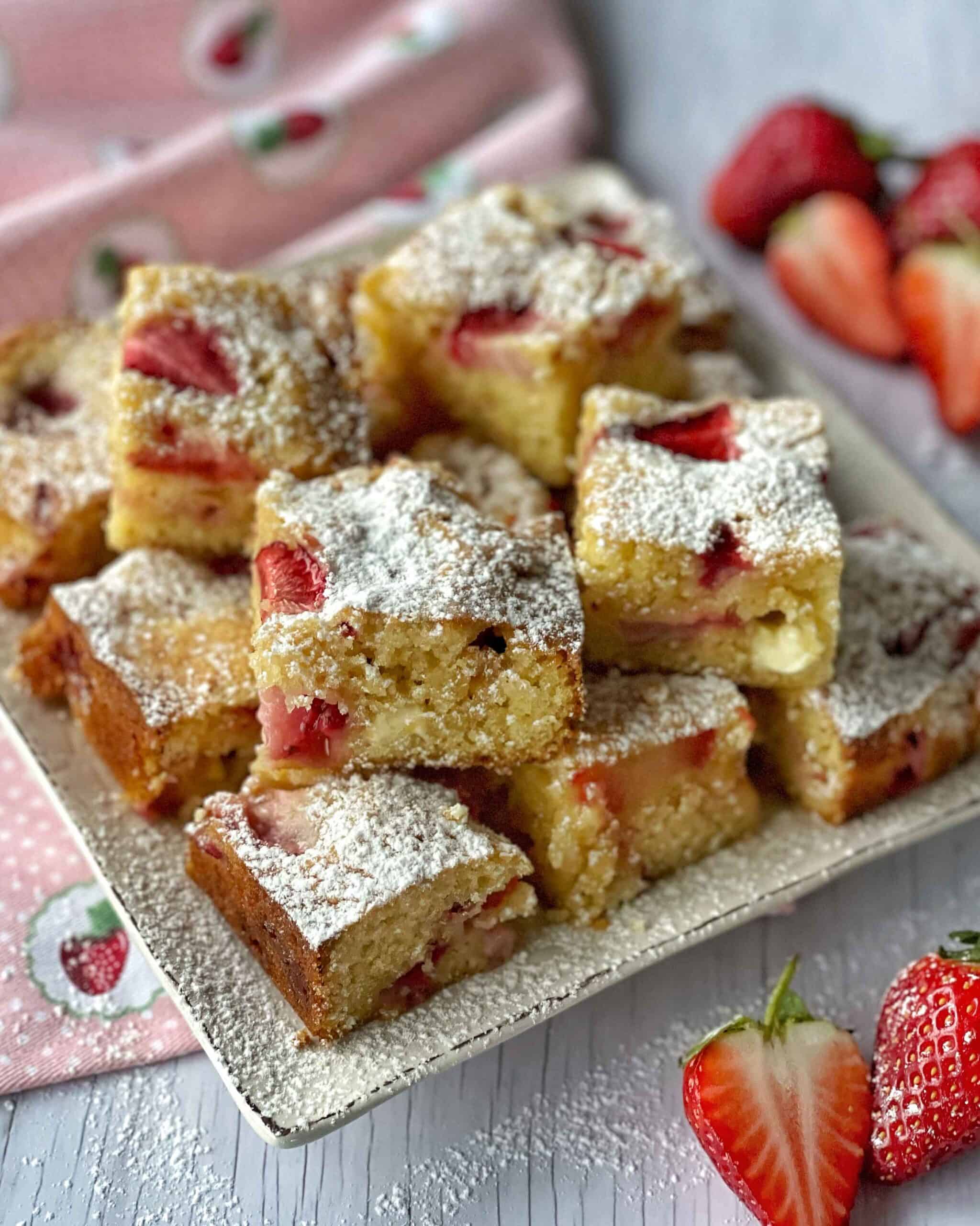A stack of white chocolate and strawberry blondies on a white plate.