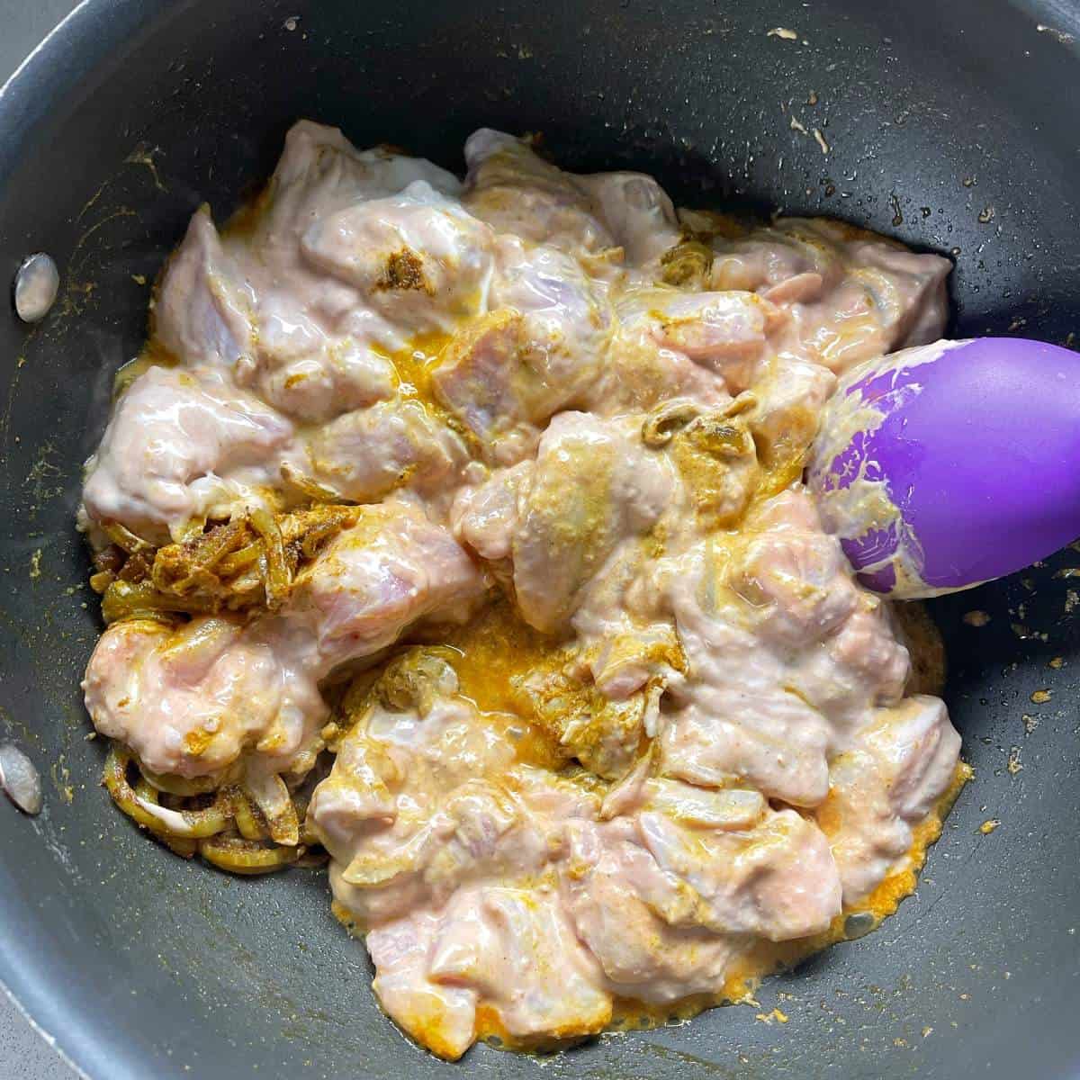 Marinated chicken frying in a pan.