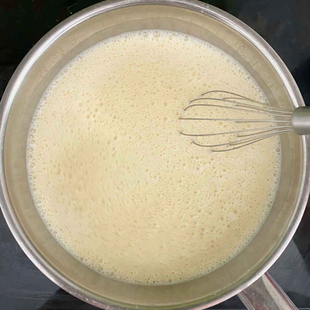 Cream in a pot on a stove top.