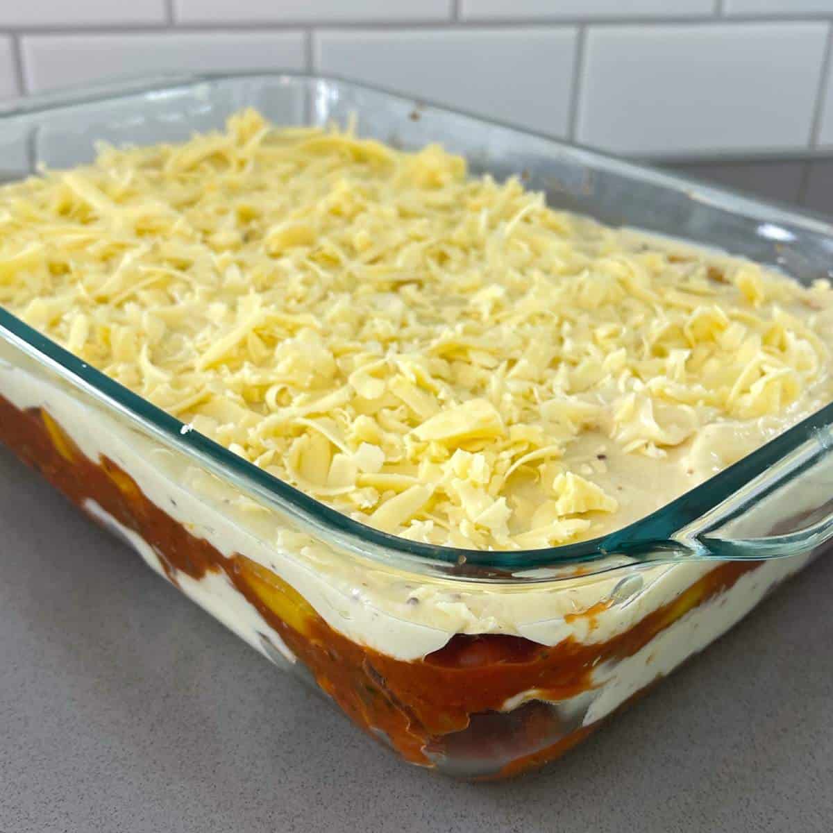Uncooked vegetarian lasagne in a glass dish showing the different layers of the lasagne