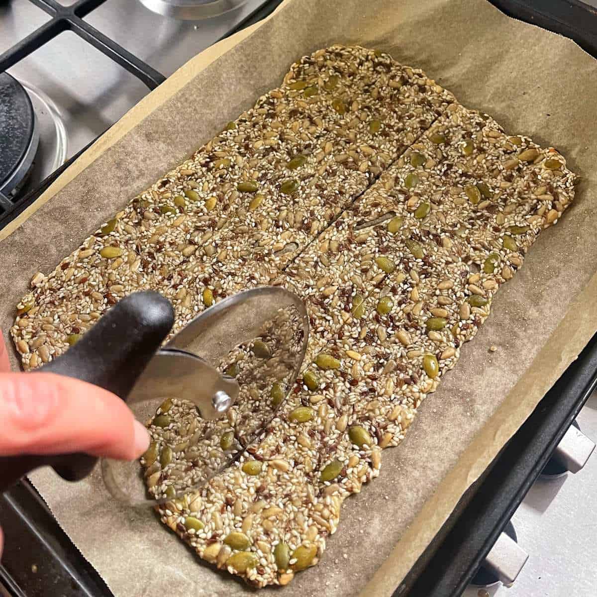 Cooked seeded crackers being sliced into small portions
