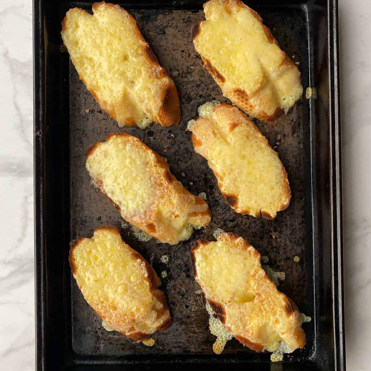 Grilled French stick slices with melted grated cheese on top