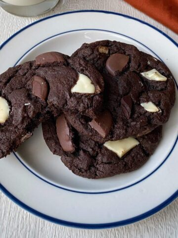 Three triple chocolate cookies on a white plate.