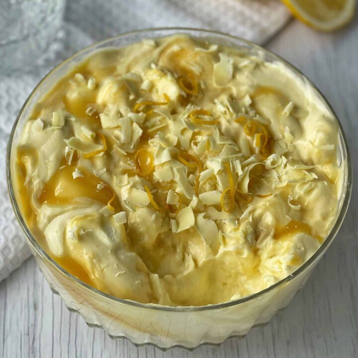 Lemon curd Ambrosia in a glass bowl on a white bench.